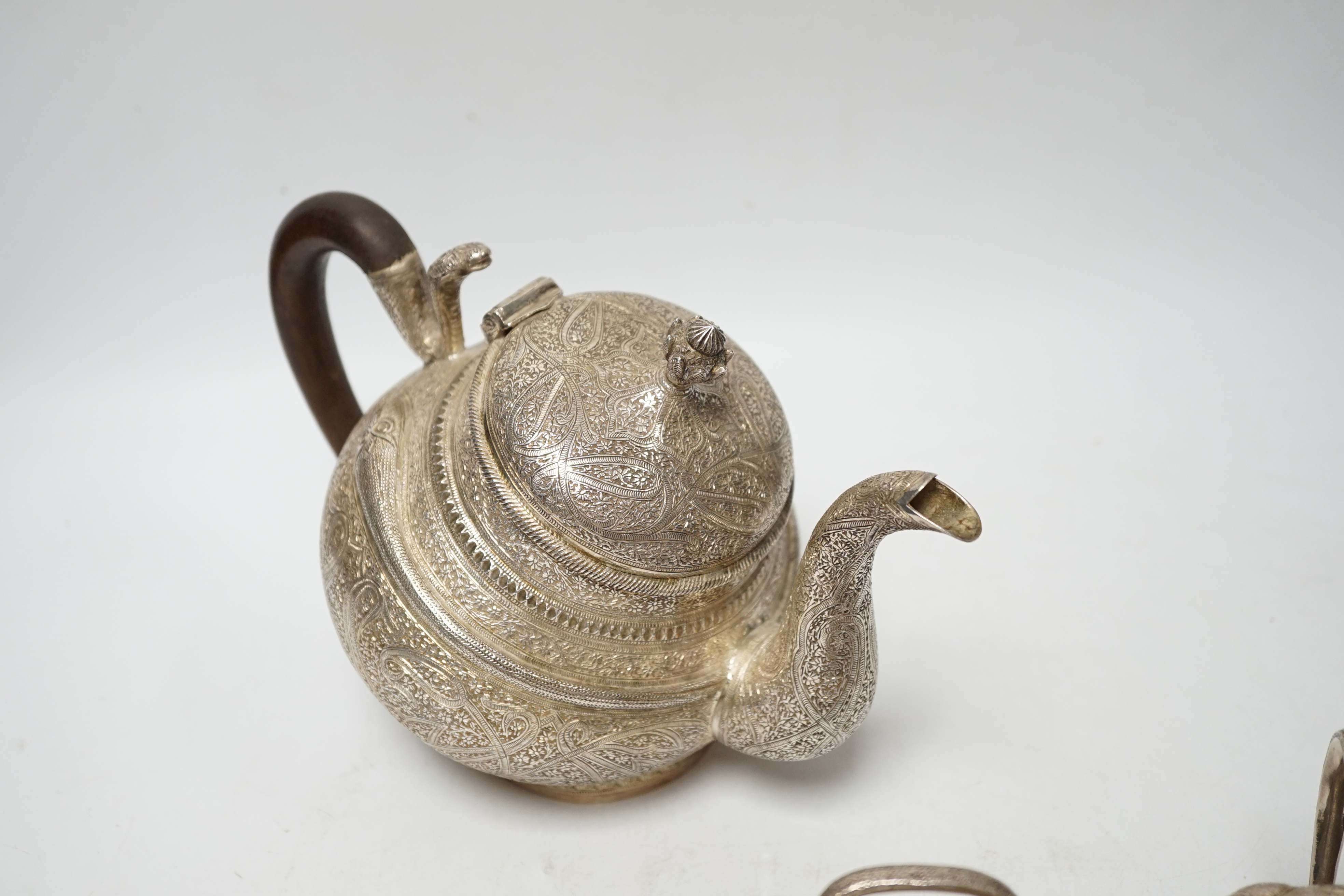 A 20th century Indian three piece embossed white metal tea set, with boteh and cobra decoration, gross weight 38.6oz.